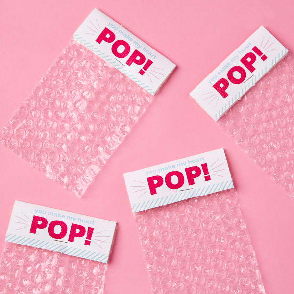 small place cards reading, 'you make my heart pop,' stapled onto plastic bubble wrap sheets
