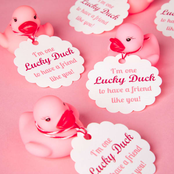 pink rubber duckies with scallop tags reading, 'I'm one lucky duck to have a friend like you' tied on with red string, sitting on pink table