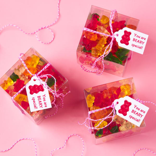 three cute scallop-topped tags with gummy bear illustrations reading, 'you are beary special,' fastened to boxes of gummy bears with pink and white string on a pink table