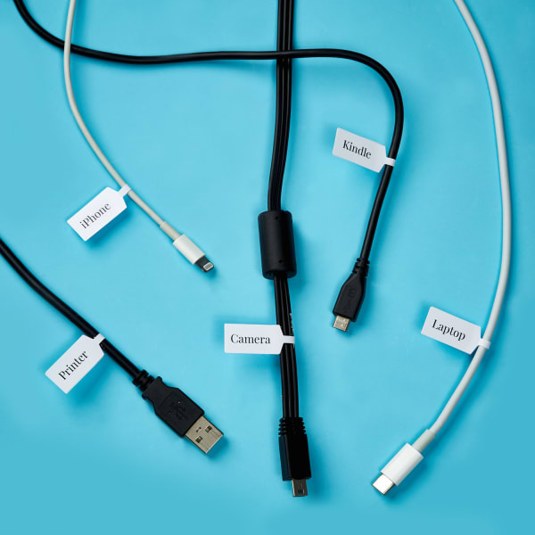 white barbell shaped labels wrapped around five black and white cables on bright blue desk