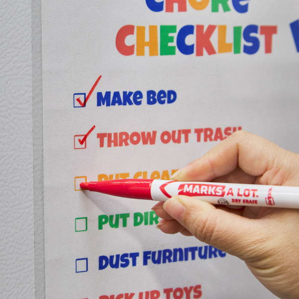 A close up of colorful kids chore chart with items being marked off as part of a family cleaning schedule.