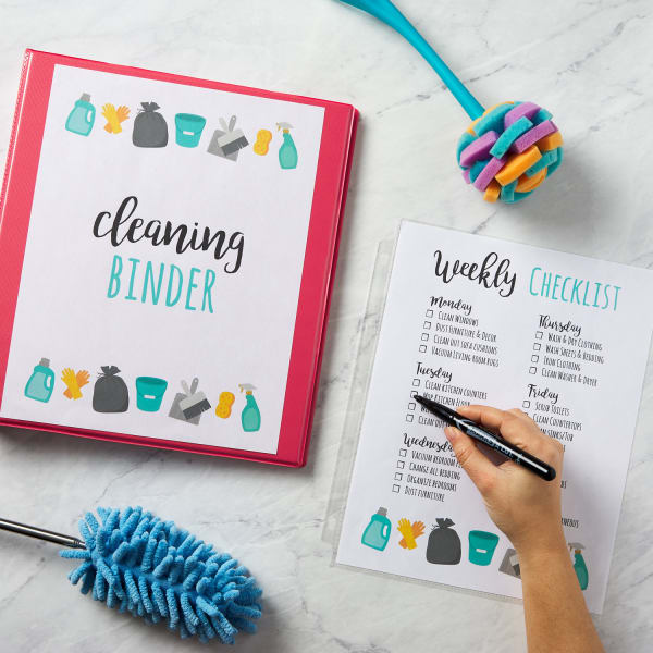 cute cleaning schedule template for a weekly checklist and cleaning binder on marble countertop with supplies and tasks being marked off