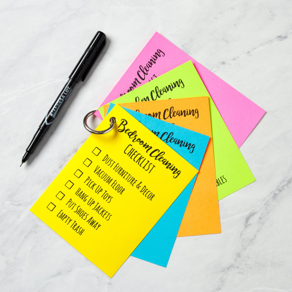 colorful cleaning checklists made with avery templates held together with a ring fanned out on a marble counter top with a marker