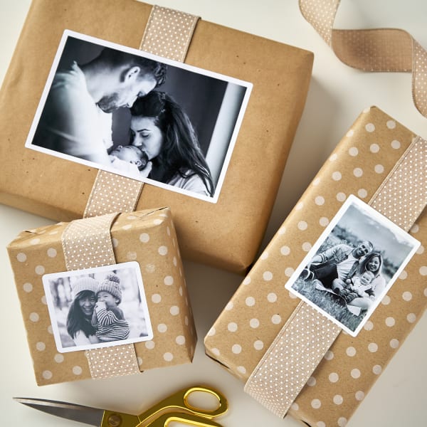 plain and polka dot kraft brown paper wrapped around three gift boxes tied with fabric ribbon and topped with personal black and white photos