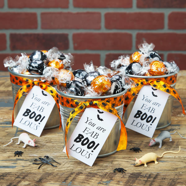 Metal buckets are filled with various candies and decorated with orange and black spider print ribbon. The buckets are finished off with a tag made from Avery business card 5371 that reads, " You are fab BOO lous!"