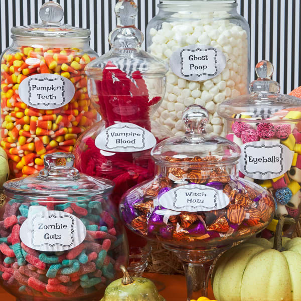 Assortment of snacks and candies in glass jars with Halloween themed labels