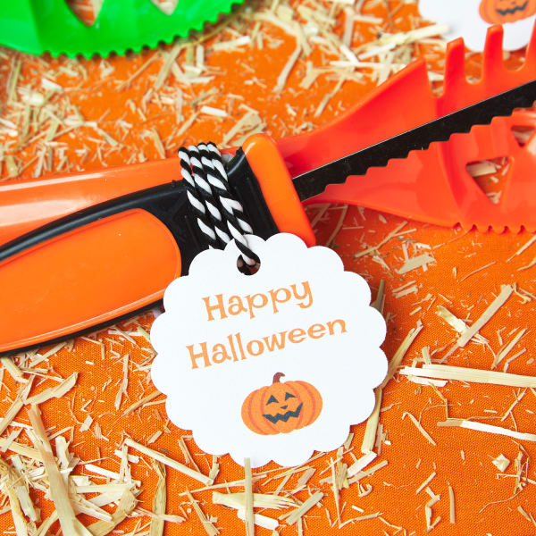 orange and black pumpkin carving toolset with a white label tied by black and white string featuring an adorable Happy Halloween themed message