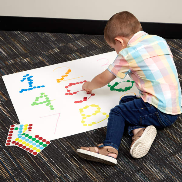 Little boy adding round stickers tracing numbers