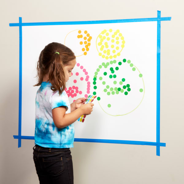 Toddler girl adding stickers to round shapes