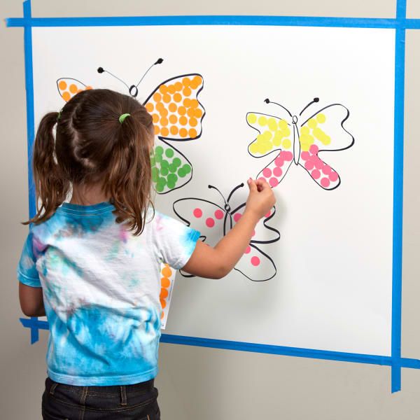 Toddler girl using neon round stickers in butterfly