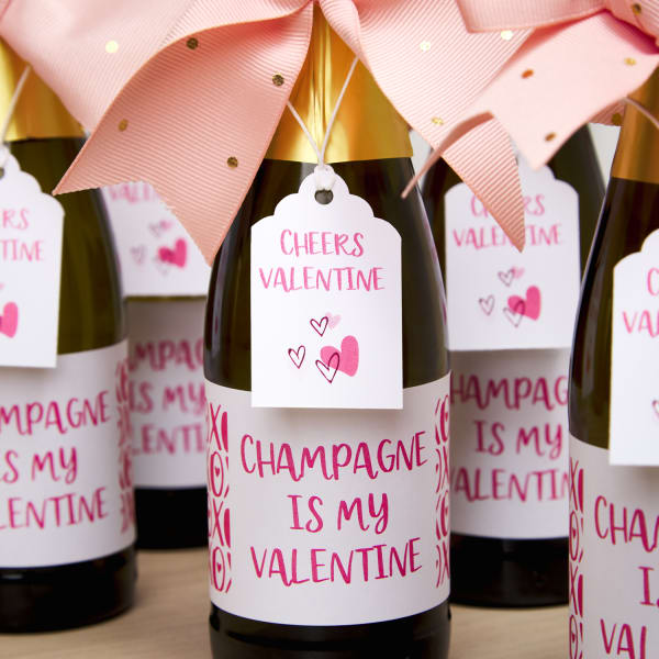 close up of decorated champagne bottles for galentines day party favors using avery labels and printable tags