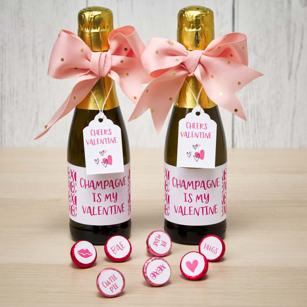 champagne bottle party favors and personalized chocolate kisses themed for a galentines day party with pink and white