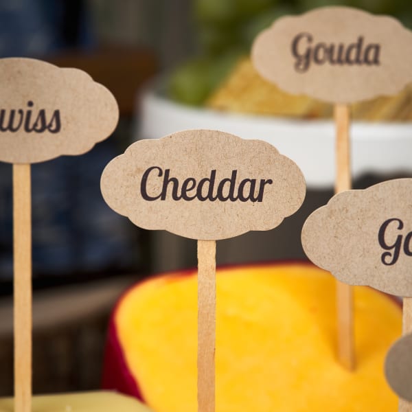 close up of scallop tag marker on various cheese such as colby, cheddar, gouda, and goat cheese