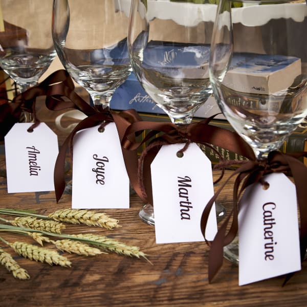 four printable tags with names tied with ribbon to stems of four wine glasses