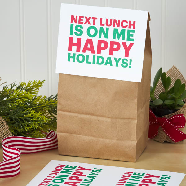paper lunch bag topped with large postcard label with festive holiday message
