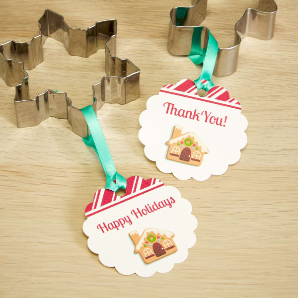 round scallop tags with candy cane and gingerbread house design tied around cookie cutter party favors with green ribbon