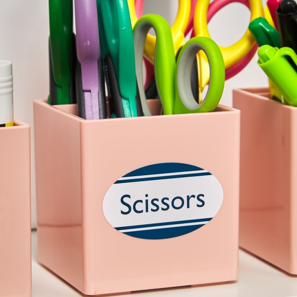 three small, square, light pink boxes holding scissors, glue, and markers with corresponding oval labels