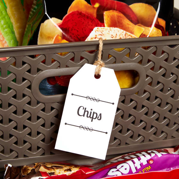 close up of a brown woven plastic snack bin filled with chips and labeled with printed tag