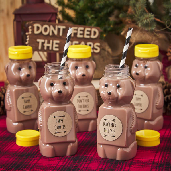 bear-shaped honey bottles refilled with chocolate milk with black and white striped straws and yellow caps