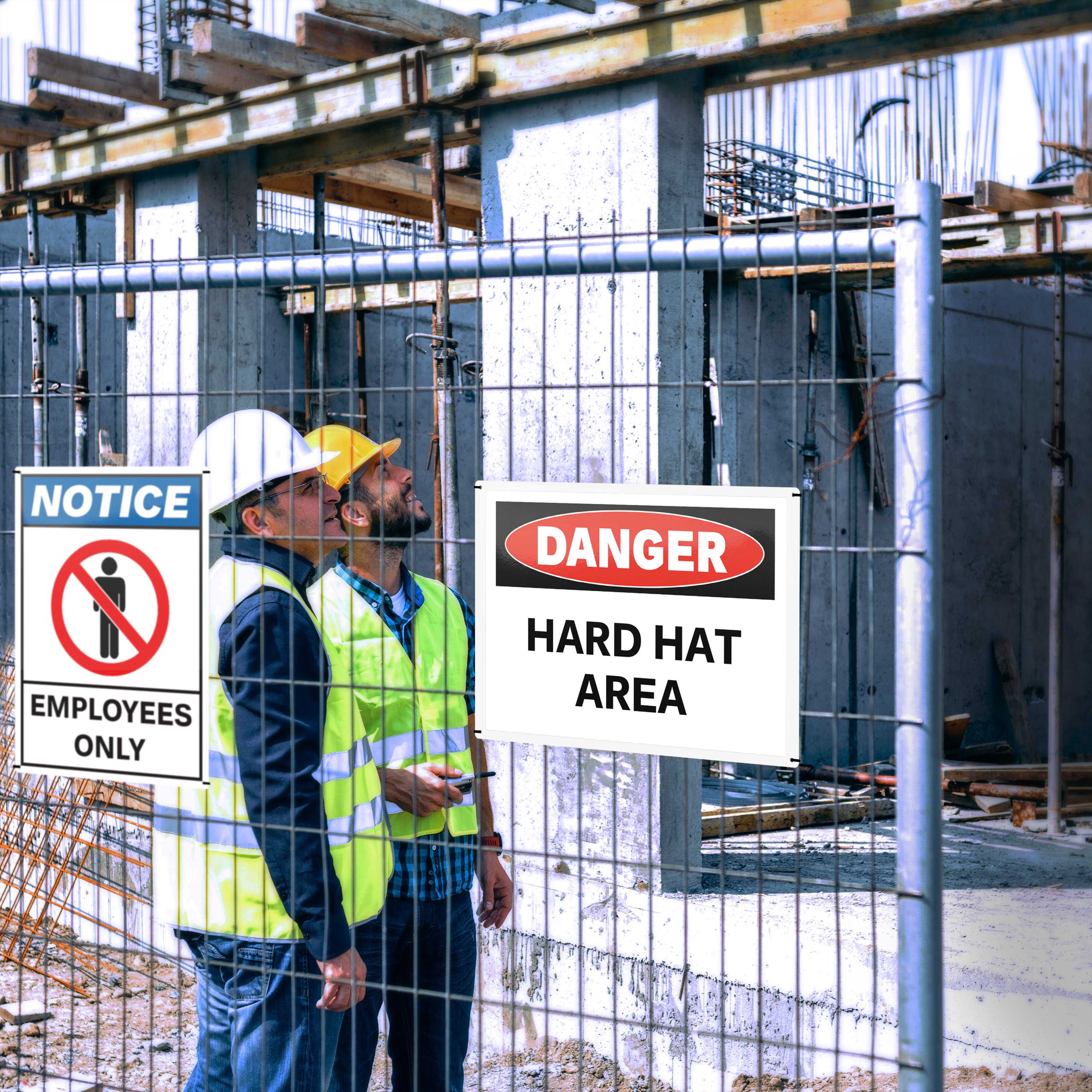 Temporary outdoor safety signs mounted on construction fencing to mark restricted and hard hat areas.