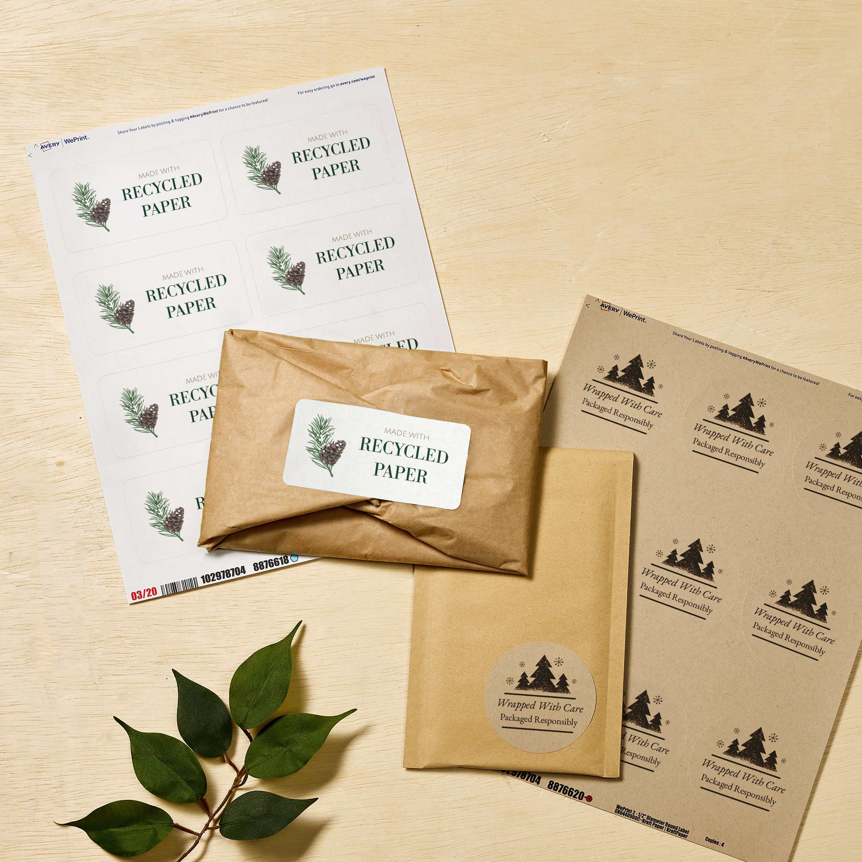 Holiday-themed eco-friendly packaging displayed on a light wood surface, featuring kraft mailers and two sets of Avery labels—one reading “Made with Recycled Paper” with pine illustrations, and another circular design reading “Wrapped With Care. Packaged Responsibly.”