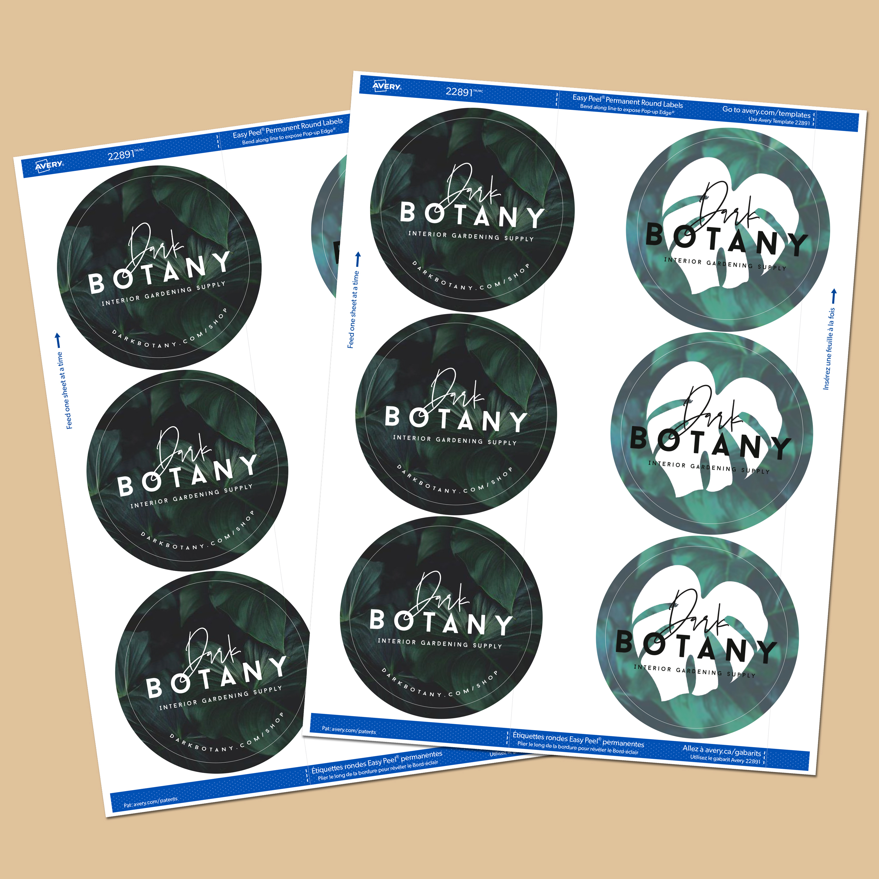 Two sheets of custom-printed round stickers with a dark botanical design and the words "Dark Botany" in an elegant script font. The stickers are printed on a kiss-cut label sheet, allowing for easy peeling while keeping the backing intact. Each sheet features six stickers, arranged in two columns of three. The background of the stickers has a moody green leaf pattern, complementing the white and gold typography. The sheets are displayed on a neutral beige surface.