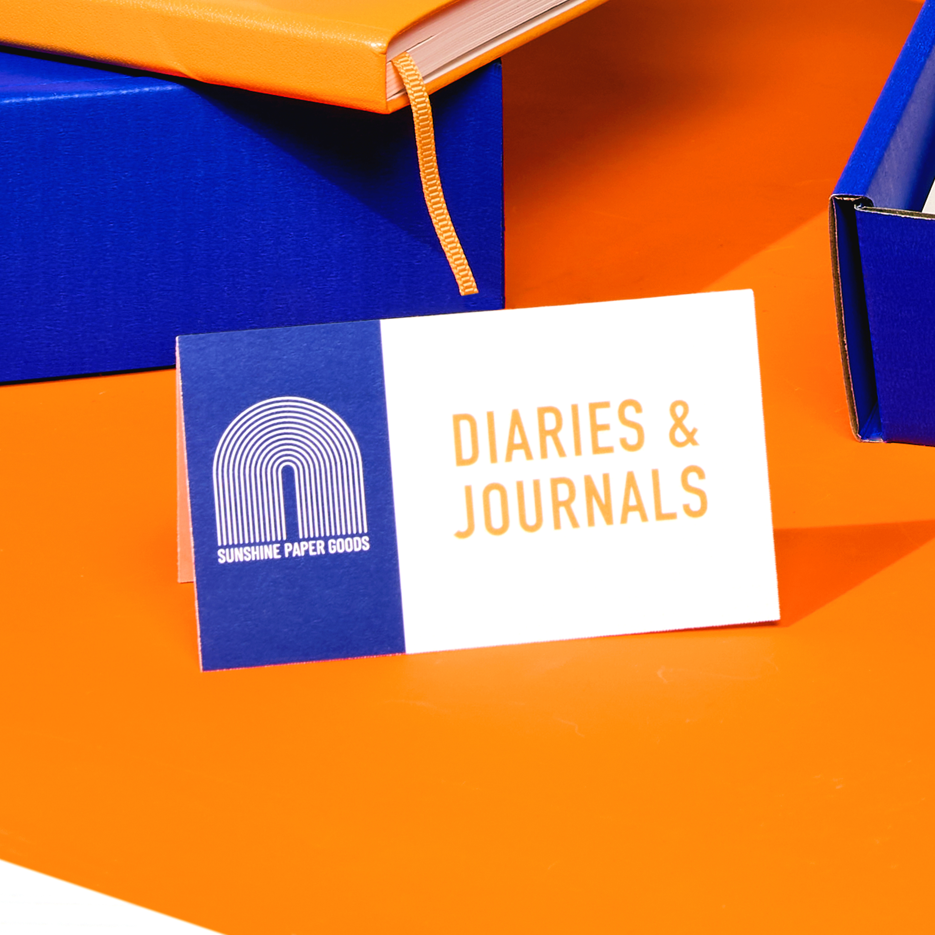 Tent card labeled "Diaries & Journals" displayed at a colorful expo booth—an example of small business marketing tools for product samples.