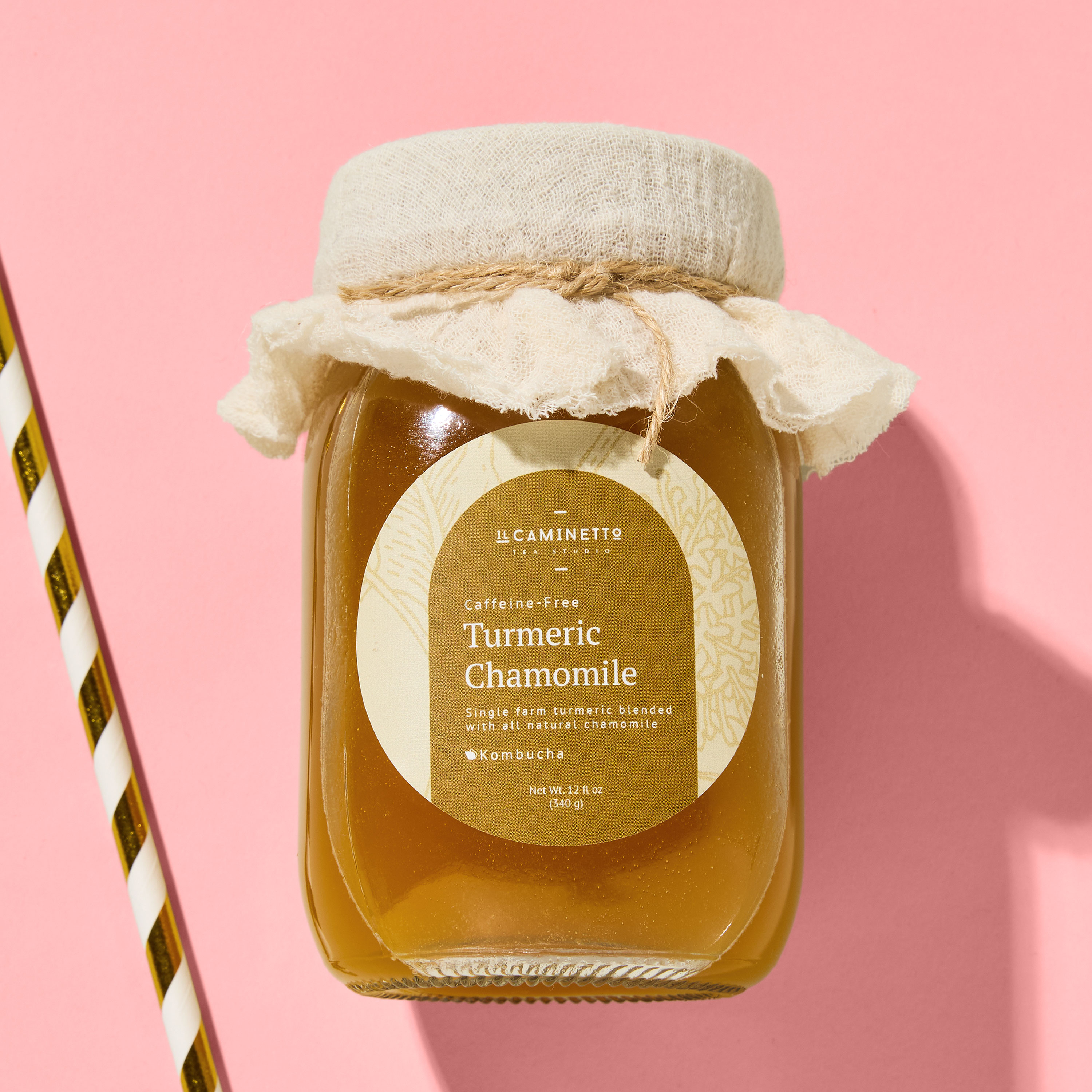 Square glass jar labeled “Il Caminetto – Turmeric Chamomile Kombucha” with a round sticker for canning jars, wrapped in rustic fabric and twine on the lid. The warm yellow tones and botanical artwork highlight an artisanal, small-batch vibe, perfect for labels for handmade items, mason jar labels, and custom labels for jars used for kombucha, tea blends, or homemade wellness products.