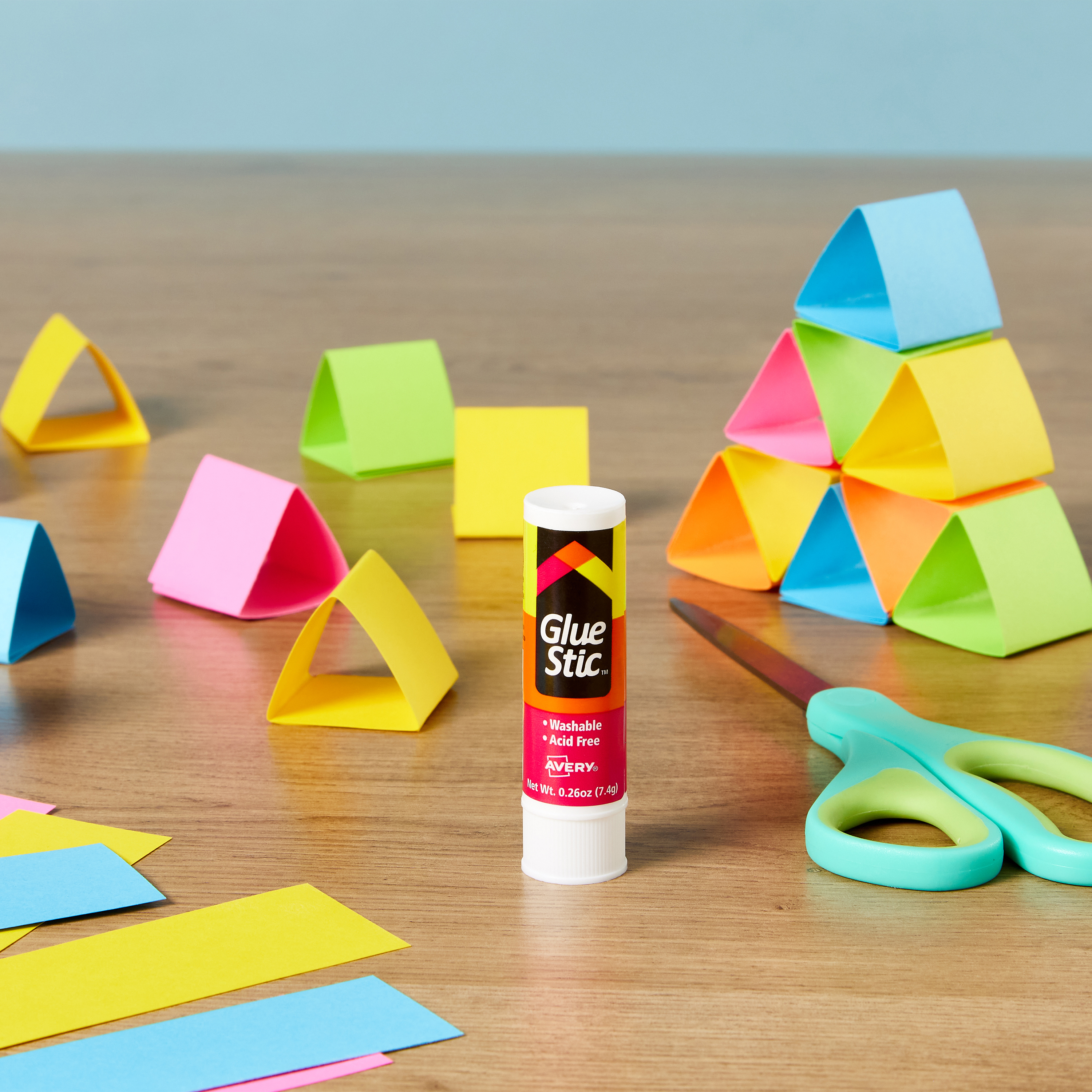 An image showing pieces of construction paper folded and glued together to create triangles that are used for building and spatial play. In the center of the image is Avery 00171 Glue Stic.