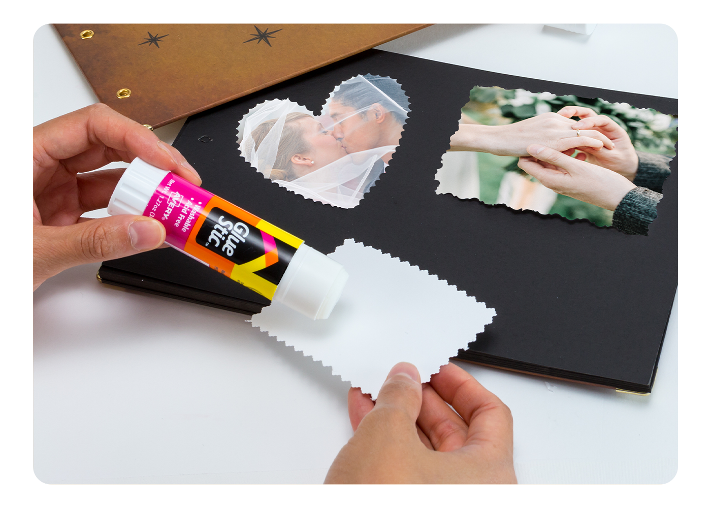 An Avery Glue Stick being used to apply photos to a wedding scrapbook