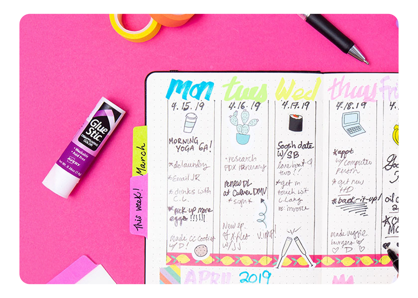 An open planner surrounded by office supplies and an Avery Glue Stick