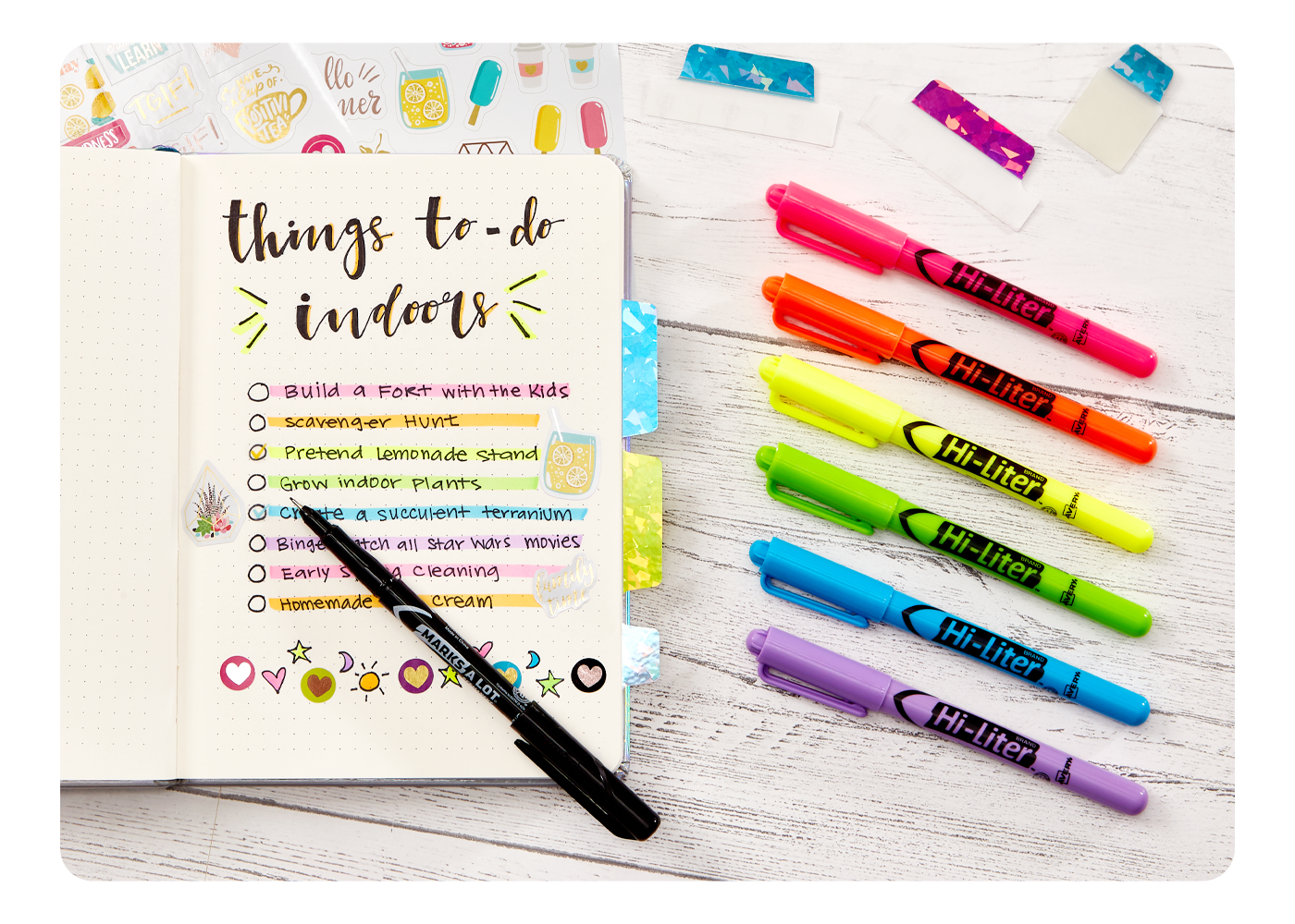 An open planner with highlighted notes with a line of Avery highlighters on the side in a spectrum of colors